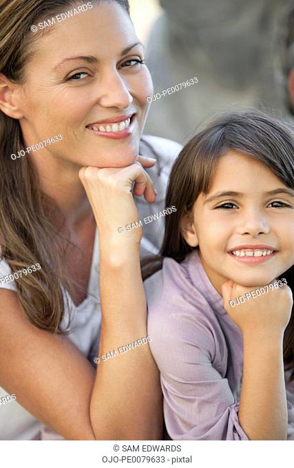 Mother and daughter sitting with hands on chins