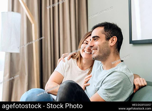 Smiling woman looking at man while sitting in hotel room