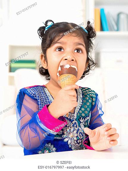 Eating ice cream. Cute Indian Asian girl enjoying an ice cream. Beautiful child model at home