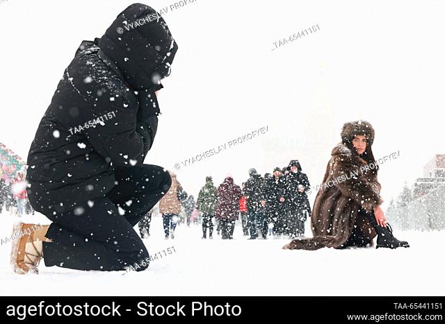 RUSSIA, MOSCOW - DECEMBER 3, 2023: A woman poses for a photo in Red Square during a snowfall with the St Basil's Cathedral in the background