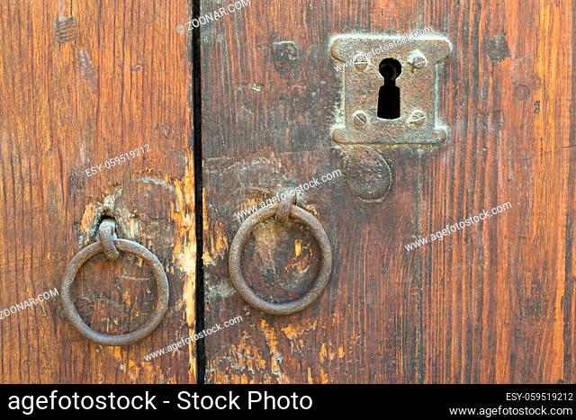 Two rusty iron ring door knobs and keyhole over an old wooden grunge door