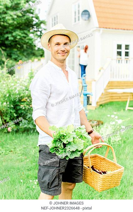 Man with basket and fresh vegetables in garden