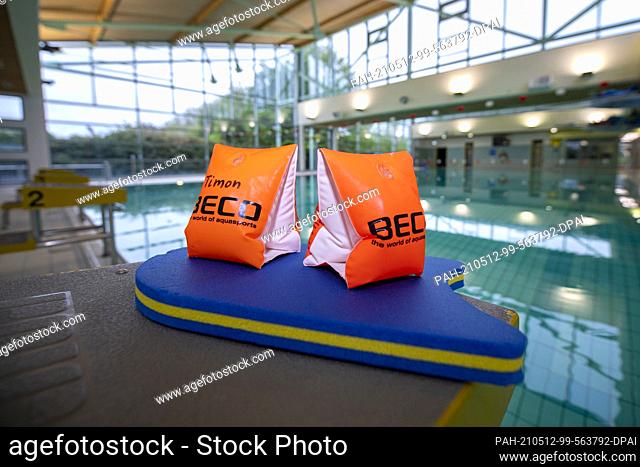 11 May 2021, Lower Saxony, Osnabrück: ILLUSTRATION - Two water wings and a swim board lie on a starting block in the Moscaubad swimming hall