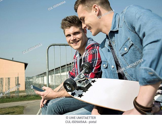 Young men in skatepark, using smartphone