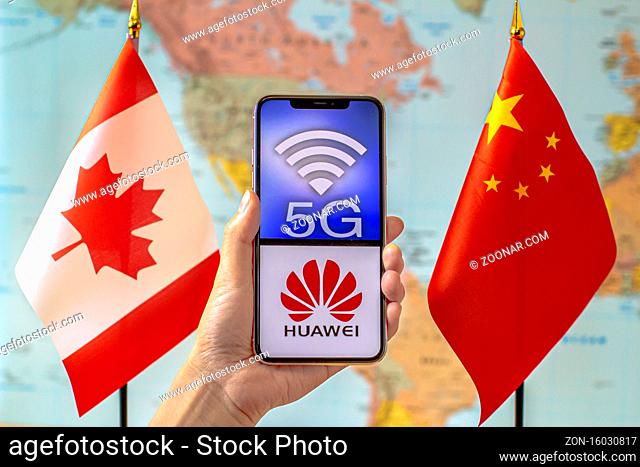 Calgary, Alberta, Canada. Sep 8, 2020. A person holding an iPhone with a 5G and Huawei logo on the screen next to a Canada and China flags on a world map