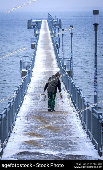 05 December 2023, Mecklenburg-Western Pomerania, Wismar: On the pier, the snow cover is spread with sand. Heavy snowfall and temperatures below freezing hinder...