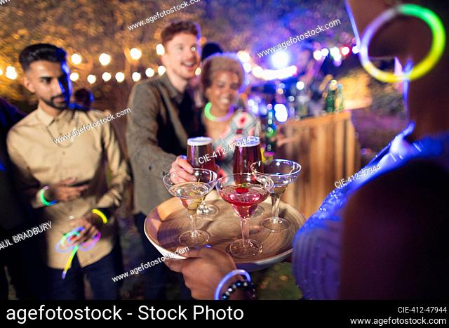 Woman serving cocktails to friends at garden party