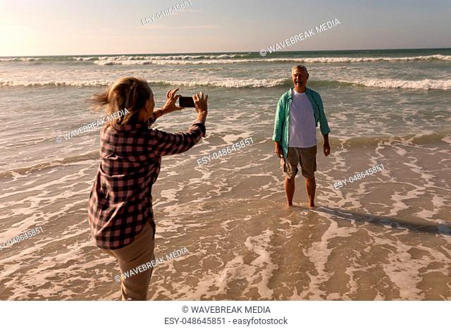 Senior woman clicking photo of senior man on the beach