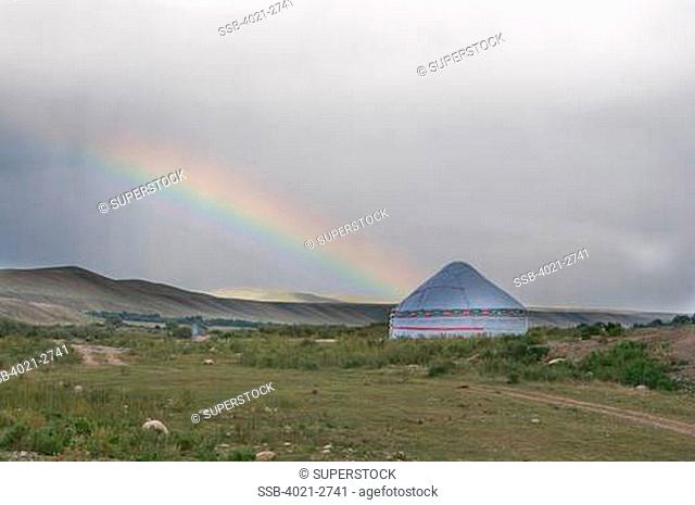 Kyrgyzstan, between Sary Chelek and Bishkek, Rainbow and tent in barren landscape