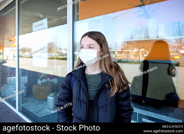 Girl with mask standing at closed shopping center