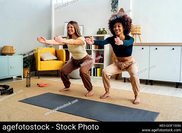 Happy women practicing squats in living room at home