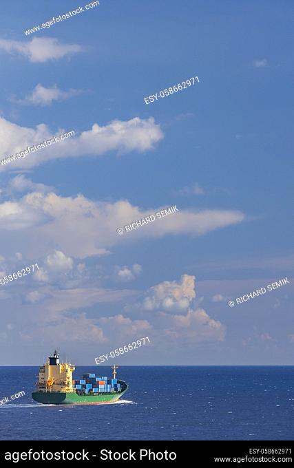 cargo ship nearby Capo Peloro Lighthouse in Punta del Faro on the Strait of Messina, most north eastern promontory of Sicily, Italy