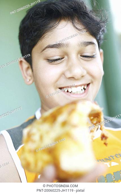 Close-up of a boy holding a slice of pizza