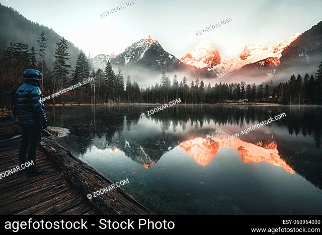 male Hiker standing at Mountain Lake watching the Sunrise in Austria - schiederweiher