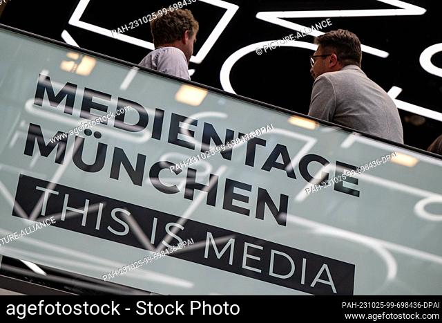 25 October 2023, Bavaria, Munich: Participants of the 37th Medientage München stand at a Medientage München logo wall. One year after the revolutionary launch...