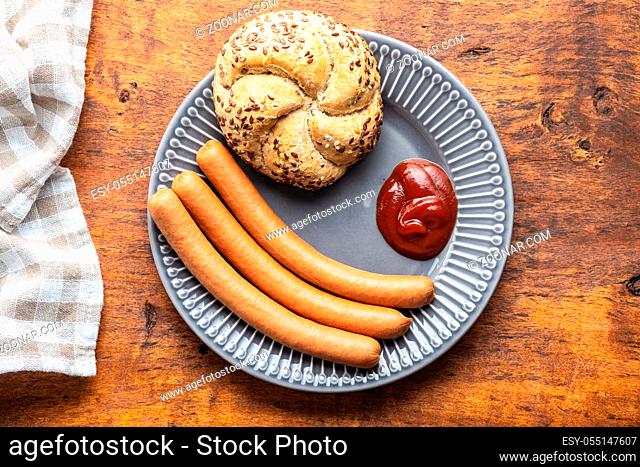 Fresh frankfurter sausages with bun and ketchup on plate. Top view