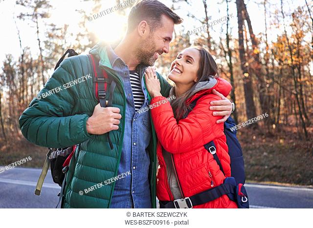 Happy couple embracing on a road in the woods during backpacking trip