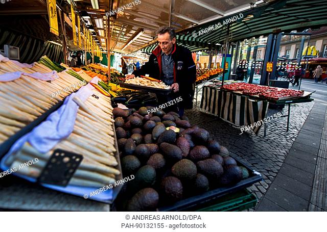 Der Mitarbeiter eines Obst- und Gemüsestandes stellt am 11.04.2017 in Frankfurt am Main (Hessen) eine Schale mit Spargel auf den Verkaufstisch