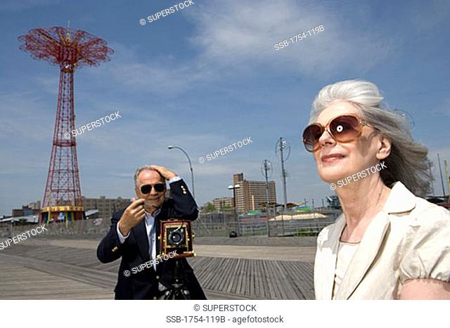 Senior man photographing a senior woman, Parachute Drop, Coney Island, New York City, New York, USA