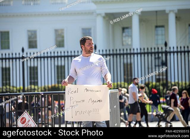 Bill Nadler, of Washington, DC, holds his protest sign as people go about their daily life while visiting outside the White House in Washington, DC, Tuesday