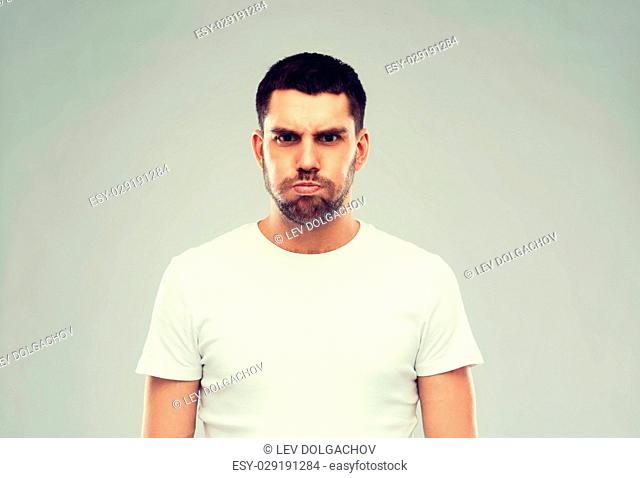 emotion, fun and people concept - man with funny angry face over gray background