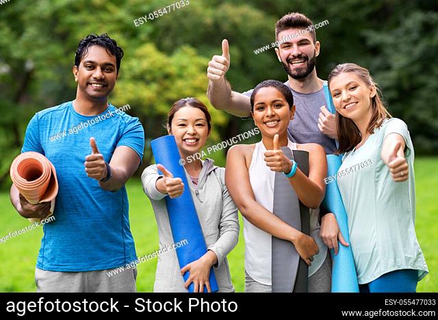 people with yoga mats showing thumbs up at park