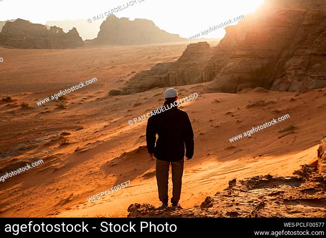 Man standing on rock in desert at sunrise