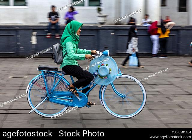 A Young Indonesian Woman Cycling In Taman Fatahillah Square, Jakarta, Indonesia