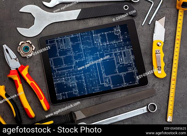 Tablet with construction tools and blueprint concept
