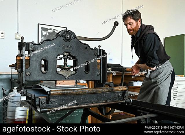 19 March 2023, Saxony-Anhalt, Halle (Saale): Ilko Köstler prints lithographs with a machine from 1895. For the Day of Printmaking