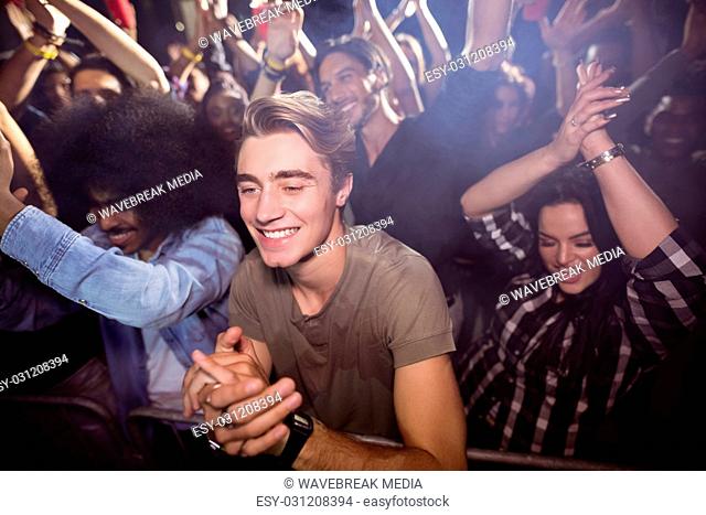 Young man amidst crowd enjoying at nightclub