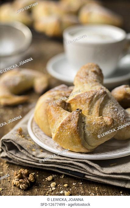 Walnut pastries with icing sugar and a cappuccino