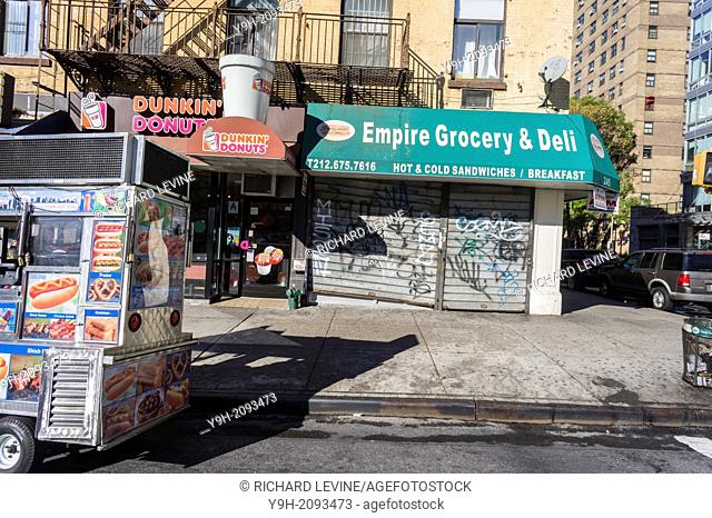 Parked hot dog cart, Dunkin Donuts and closed deli in the Chelsea neighborhood of New York