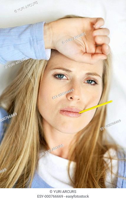Closeup portrait of a young ill woman checking her body temperature