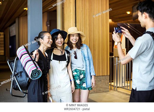 man taking a photograph of three young women