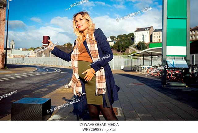 Pregnant woman waving at bus stop