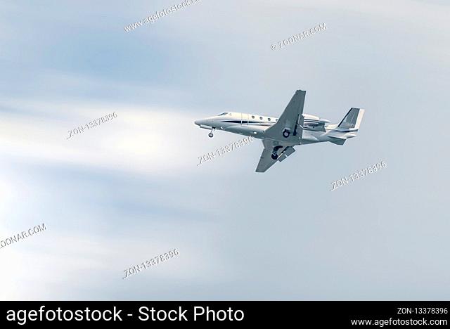 Small commercial airplane flying at low altitude under a blue sky