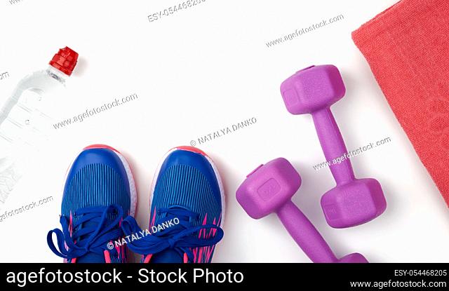 pair of blue sneakers, plastic dumbbells for sports on a white background, sports backdrop, top view, copy space