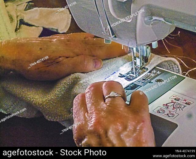 Closeup of mature woman working with sewing machine at home