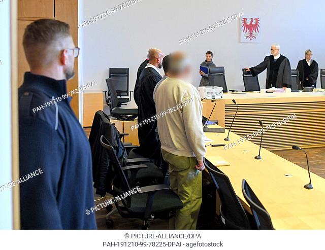 10 December 2019, Brandenburg, Frankfurt (Oder): The defendant (M) in the drug trial waits next to an interpreter and his lawyer in the hall of the district...