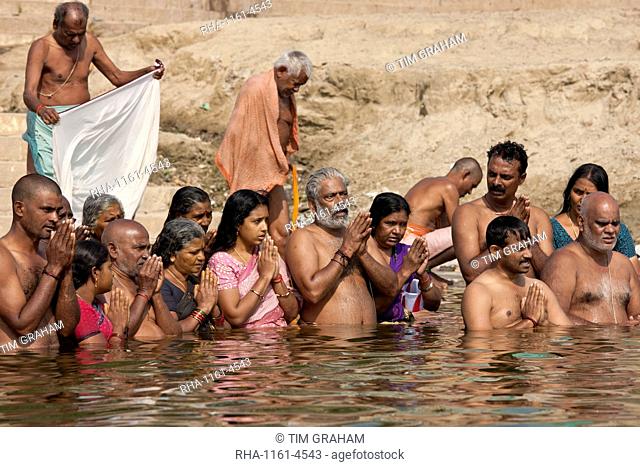 Indian Hindu men and women bathing and praying in the River Ganges by Kshameshwar Ghat in holy city of Varanasi, India