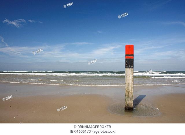 Red wooden post against blue sky on the beach, Texel, Netherlands, Netherlands, Europe