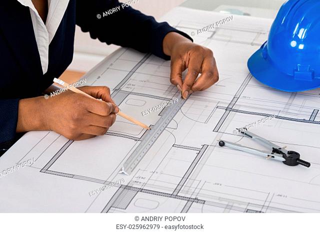 Close-up Of A Businesswoman Drawing Blueprint At Office Desk