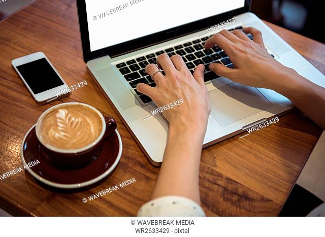 Businesswoman using laptop at café table