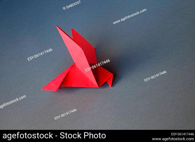Red paper dove origami isolated on a blank grey background