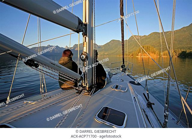 two women sitting on deck of sailboat in Desolation Sound watching the sunset on mountains, British Columbia, Canada, Darrel Giesbrecht