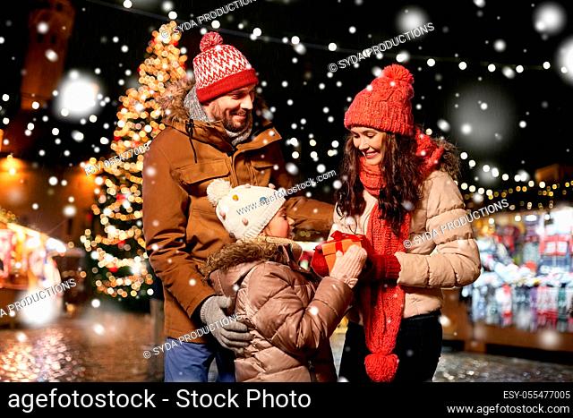happy family with gift at christmas market in city