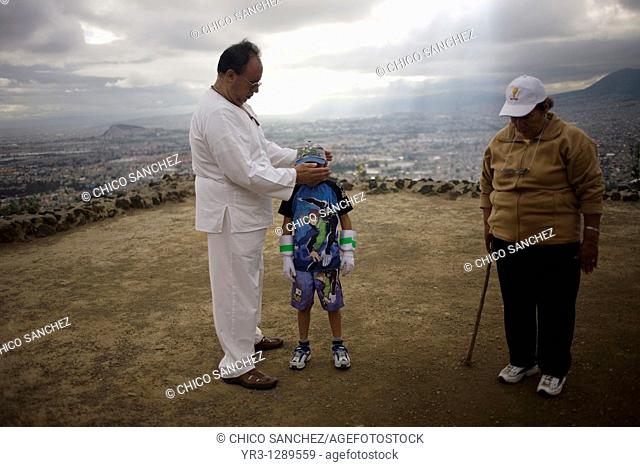 A boy receives Reiki on the top of the Cerro de la Estrella Hill of the Star pyramid, Iztapalapa, with Mexico City in the background, November 23