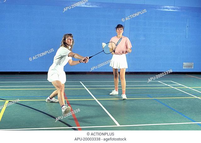 Two women playing badminton