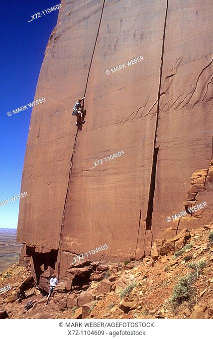 Man, rock climbing The Wiggins 1 route on the Cliffs Of Insanity in Indian Creek Canyon, Utah